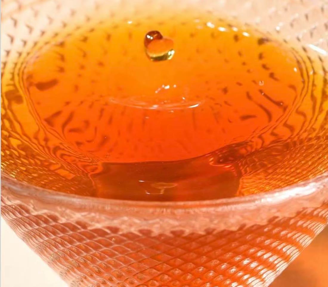 Bright orange-red tea in a clear glass cup